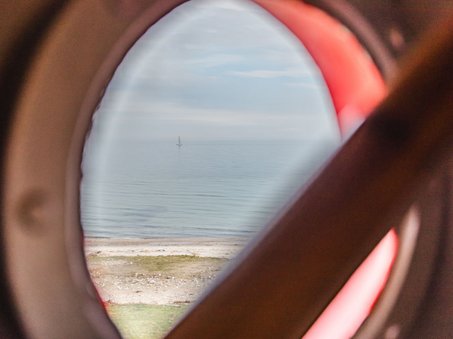 Blick aus einem Bullauge des Leuchtturms auf das Wasser